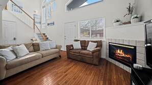 Un salon avec une cheminée, un plancher en bois et deux canapés.