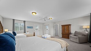 Une chambre spacieuse avec un grand lit, un ventilateur de plafond et une armoire en bois.