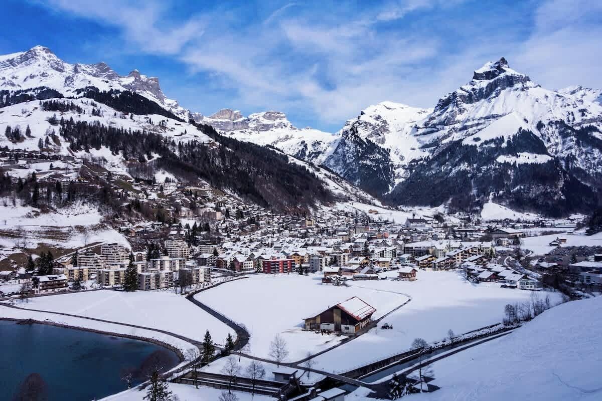 Eine verschneite Bergstadt mit Häusern und einem See.