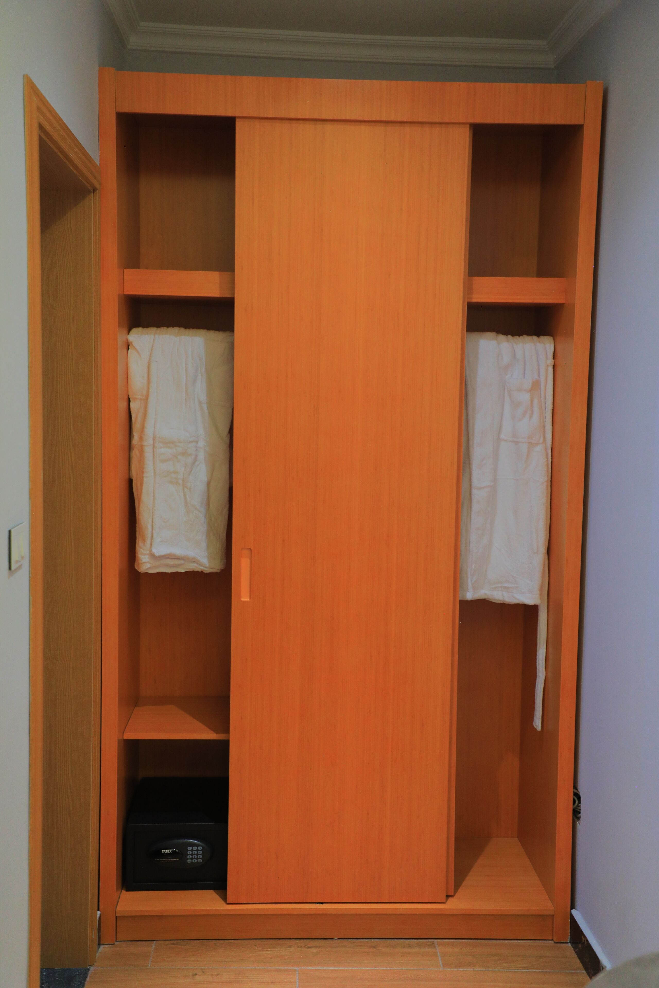 A wooden wardrobe with two doors, a shelf, and a small compartment at the bottom.
