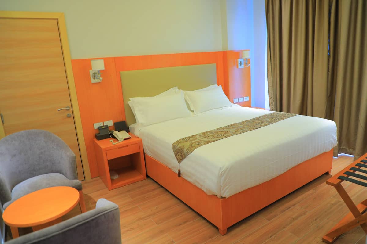 Una habitación de hotel con una cama, una silla, una mesita y una mesita de noche.