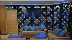 A modern living room with a sofa set, a TV mounted on a patterned wall, and a wooden door. - Libanos Hotel (Mek'ele)