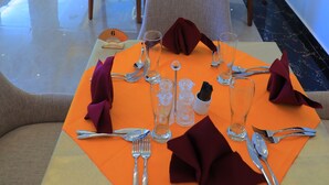A dining area with tables set for four, each with a tablecloth, cutlery, and napkins. - Libanos Hotel (Mek'ele)