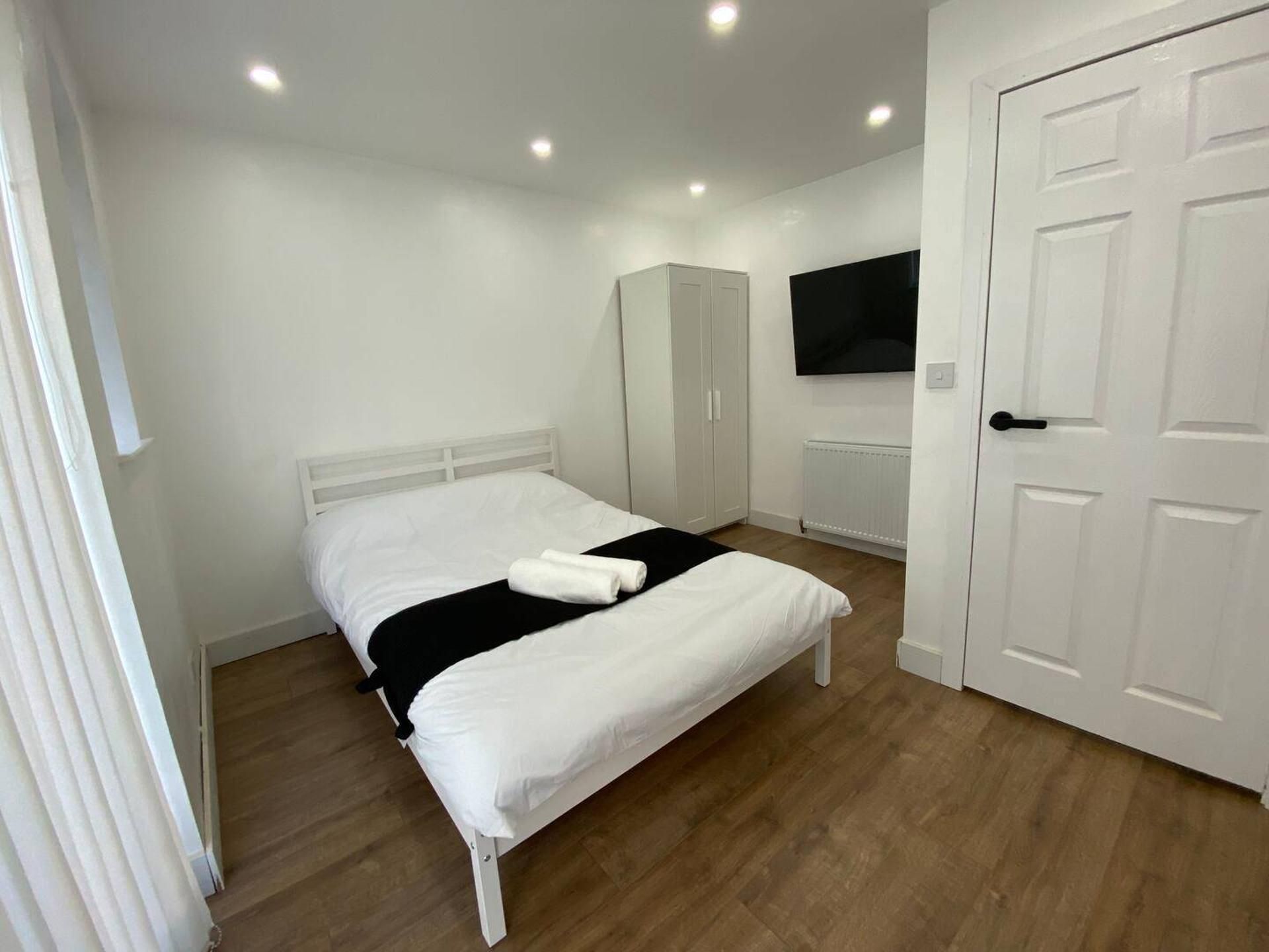Quarto com cama, guarda-roupa, televisão e porta.