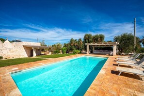 A rectangular swimming pool with a stone deck, a pergola with seating, and a stone building in the background. - Trullo GiaMar · Private pool in olive grove, 3 bedrooms, dogs welcome · Ostuni (Ostuni)