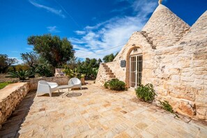 A stone building with a conical roof, a patio with chairs, and a staircase leading to the entrance. - Trullo GiaMar · Private pool in olive grove, 3 bedrooms, dogs welcome · Ostuni (Ostuni)