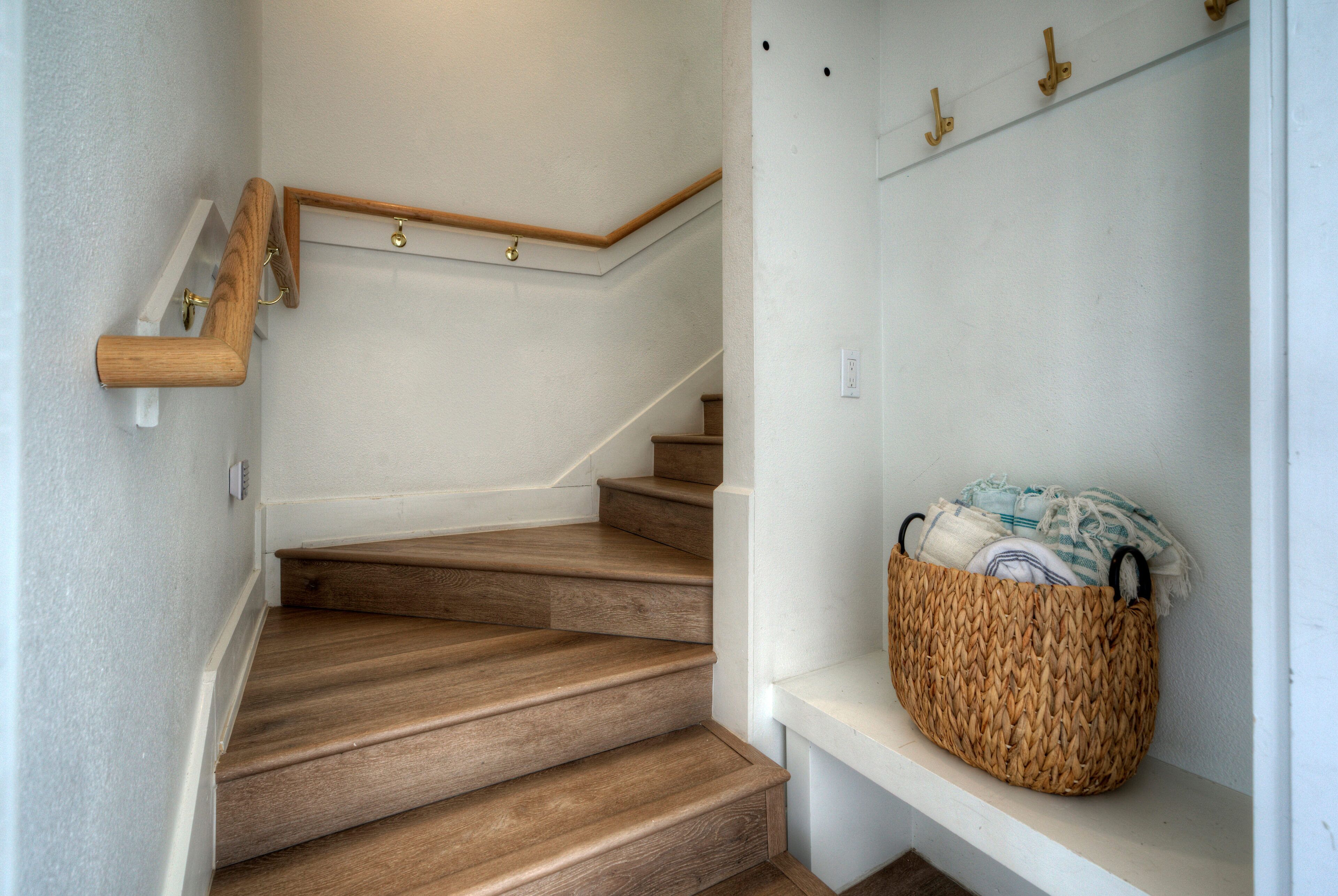 A wooden staircase with a white wall and a woven basket on the landing.