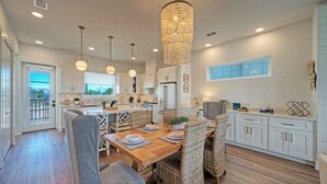 Une cuisine spacieuse avec une table à manger en bois, des chaises en osier et des luminaires suspendus.