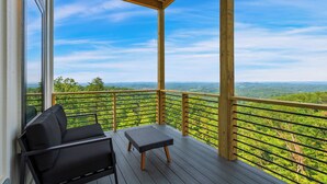 A covered outdoor seating area with a view of a forested landscape.