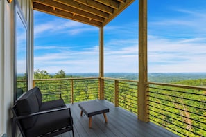 A covered outdoor seating area with a view of a forested landscape.