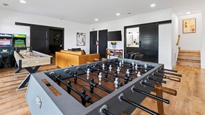 A modern living room with a foosball table, a sofa, and a TV.