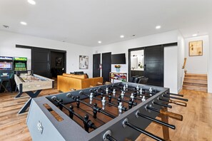 A modern living room with a foosball table, a sofa, and a TV.