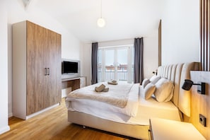 Une chambre à coucher avec un lit, une armoire, une télévision et une fenêtre avec des rideaux.