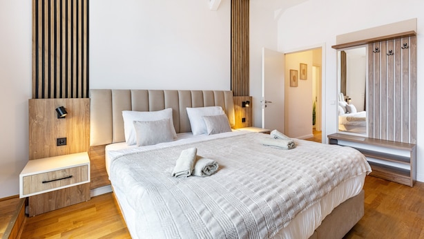 Une chambre moderne avec un grand lit, des tables de chevet, une armoire et un miroir.