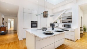 Une cuisine moderne dotée d’un îlot central, de meubles blancs et d’une verrière.