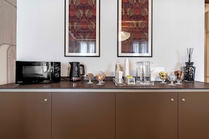 A kitchen with a microwave, coffee maker, and various glassware on the counter. - Locanda Art Deco' (Venice)
