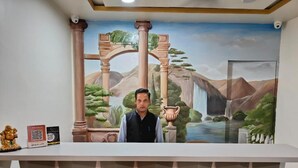 Un mostrador de recepción con un mural que muestra un paisaje con montañas, árboles y una cascada.