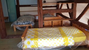 A rustic room with two wooden bunk beds, a blue door, a star-shaped wall decoration, and a wooden ceiling beam structure.
