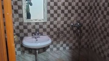 Un baño con pared de baldosas a cuadros, un lavabo y un espejo.