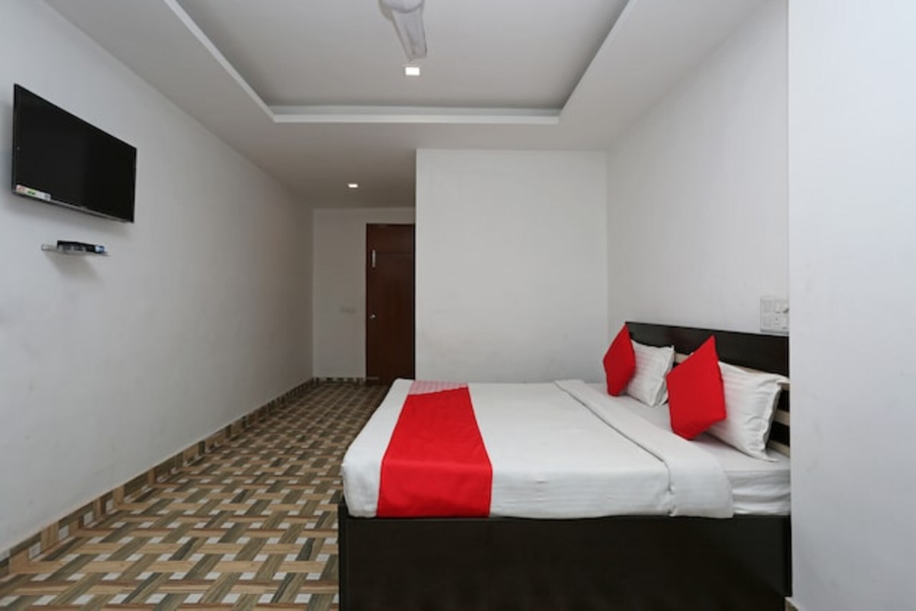 Quarto de hotel com uma cama, televisão e piso estampado.
