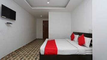 Quarto de hotel com uma cama, televisão e piso estampado.