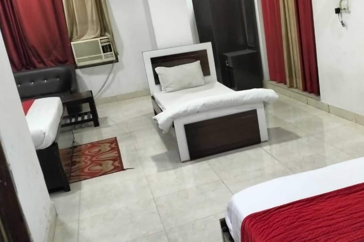 Une chambre d’hôtel avec un lit, un canapé, une petite table et une fenêtre avec des rideaux.