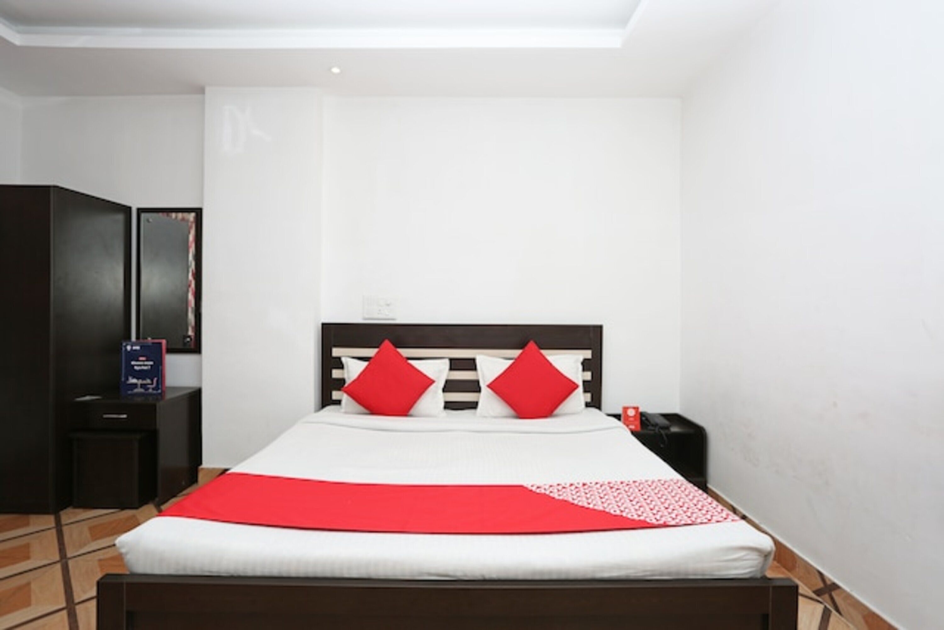 A hotel room with a bed, a nightstand, a wardrobe, and a framed picture on the wall.