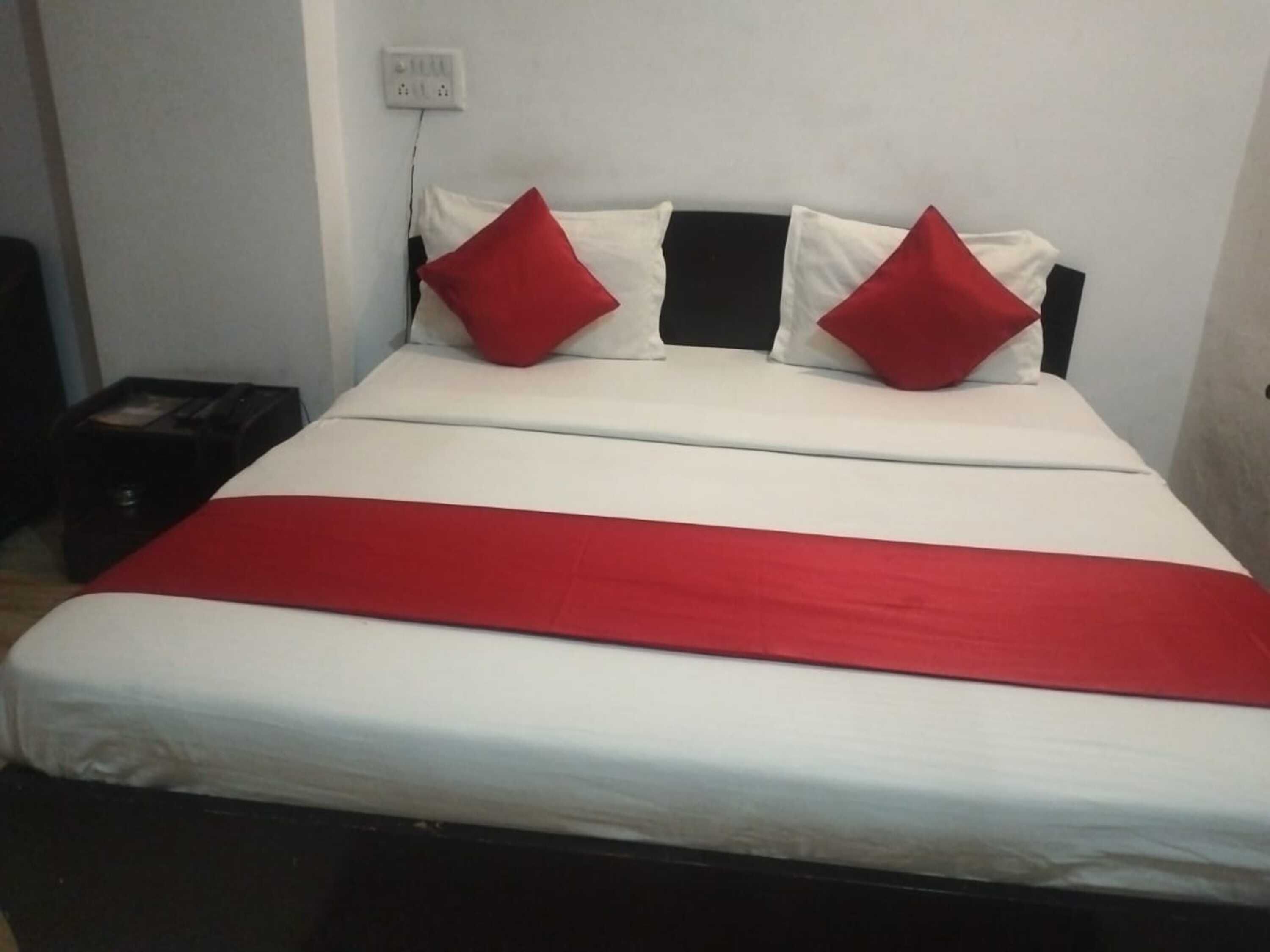 A bed with a white and red bedspread, two red pillows, and a black headboard.
