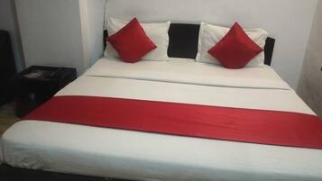 A bed with a white and red bedspread, two red pillows, and a black headboard.