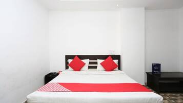 Ein ordentlich eingerichtetes Hotelzimmer mit einem Bett, einem Nachttisch und einem kleinen Tisch.