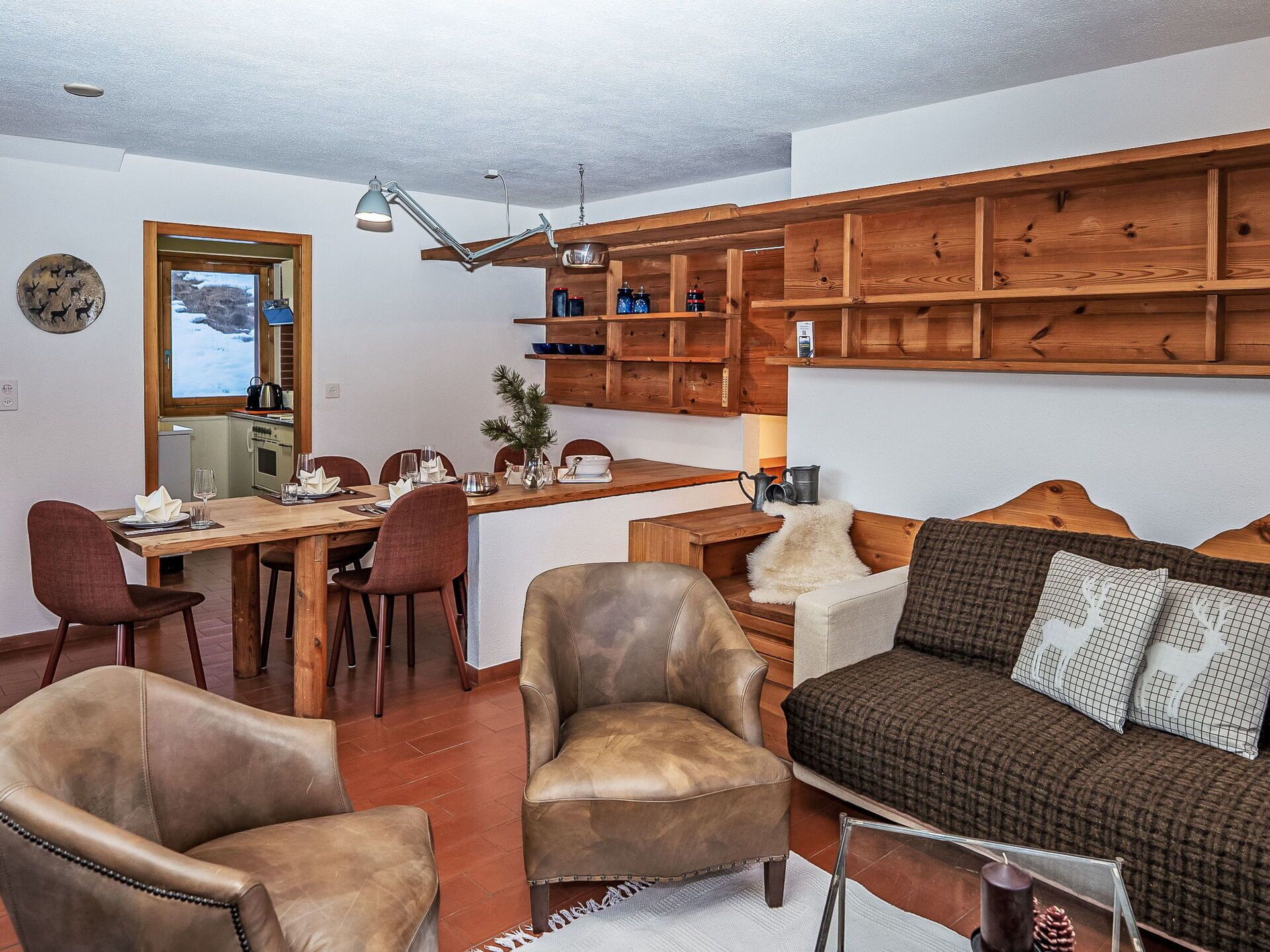 Ein gemütliches Wohnzimmer mit Ledersesseln, einem Holztisch und einer Couch mit gemusterten Kissen.