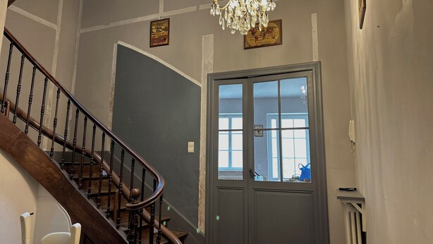 A staircase with a wooden handrail and a chandelier.