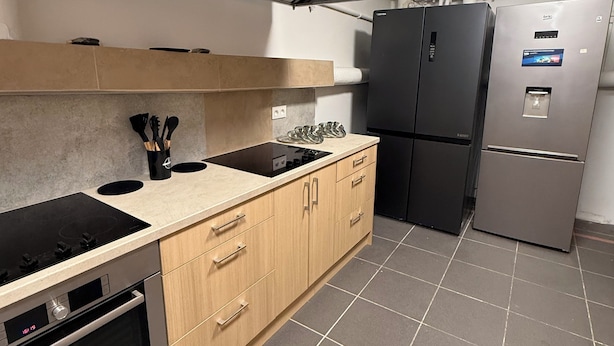 A modern kitchen with a built-in oven, a stove, and a refrigerator. - HOSTEL PULSE (Warsaw)