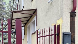 A gated entrance with a metal gate, a concrete pathway, and a building with a beige facade. - HOSTEL PULSE (Warsaw)