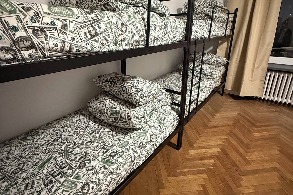 A bunk bed with patterned bedding, a radiator, and a window with curtains.