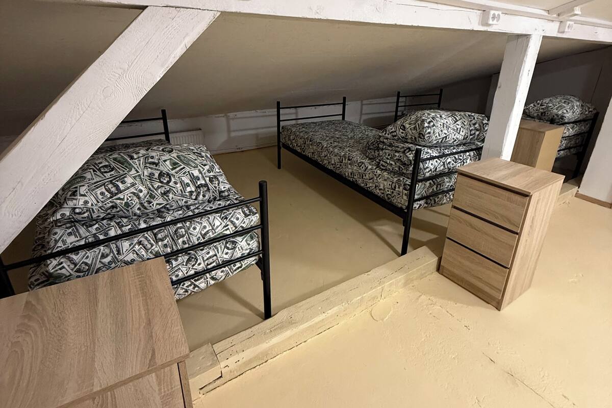 A dormitory room with bunk beds, a wooden dresser, and a white ceiling.