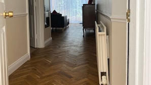 A hallway with wooden flooring, white walls, and a radiator on the right. - Byways Apartments (Salisbury)