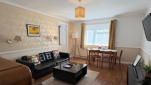 A modern living room with a sofa, coffee table, and dining area. - Byways Apartments (Salisbury)