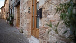 A narrow cobblestone street lined with traditional stone buildings, featuring wooden doors and small potted plants. - Les Portes de Castelnau - A haven of peace (Castelnau de Montmiral)