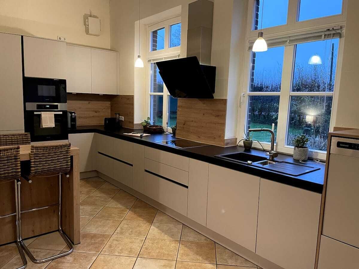 A modern kitchen with a black countertop, white cabinets, and a window with a view of the outdoors.