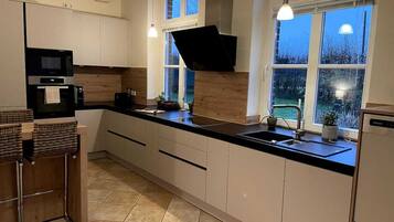 A modern kitchen with a black countertop, white cabinets, and a window with a view of the outdoors.