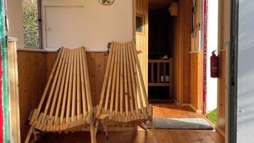 Un intérieur en bois avec deux chaises à lattes, un plancher en bois et une porte donnant sur un espace extérieur.