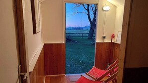A wooden interior with a view of a grassy field and a tree. - Landhaus Baumberge - Cozy vacation home & sauna (Billerbeck)