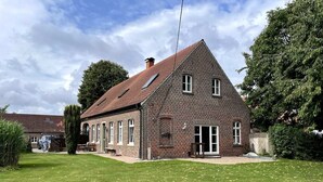 A two-story brick house with a sloped roof, a front porch, and a well-maintained lawn. - Landhaus Baumberge - Cozy vacation home & sauna (Billerbeck)