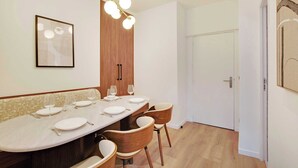 Zona pranzo con un tavolo lungo apparecchiato per quattro persone, sedie in legno, un lampadario moderno e un'opera d'arte incorniciata appesa al muro.