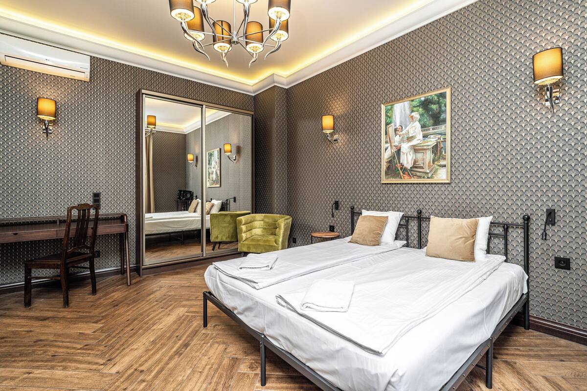 A modern hotel room with a large bed, a desk, and a mirror.