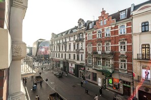 Straßenansicht einer europäischen Stadt mit historischen Gebäuden, blauem Himmel und Fußgängern.