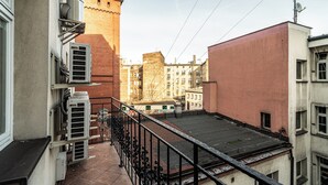 A narrow urban street with buildings on both sides, a metal fence, and a clear sky. - RentPlanet - Apartamenty Stawowa (Katowice)