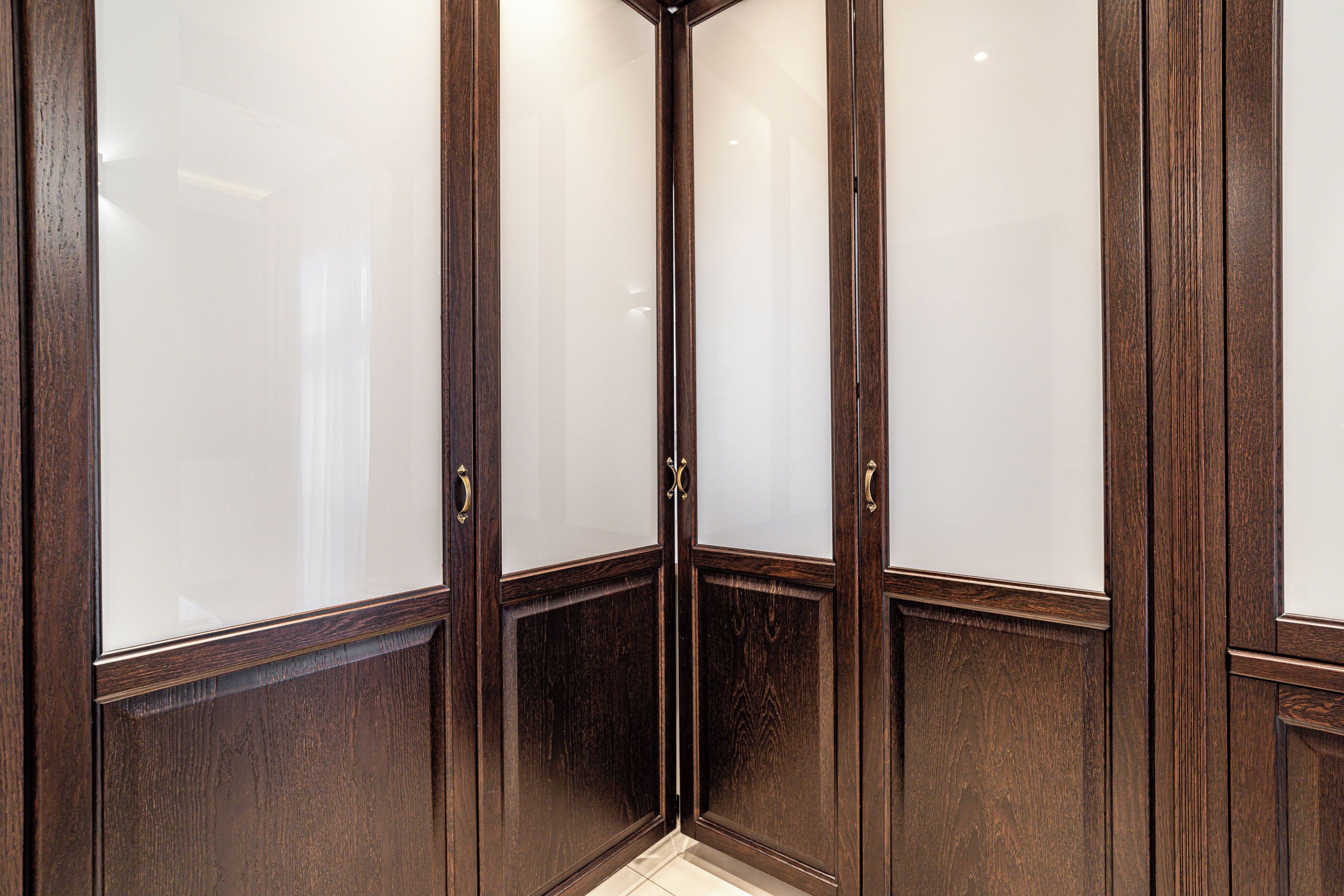 A corner of a room with wooden paneling and frosted glass doors.