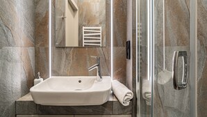A bathroom with a white sink, a mirror, and a glass shower enclosure. - RentPlanet - Apartamenty Stawowa (Katowice)